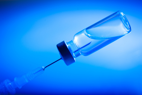 Preparation for vaccination, syringe filled with vaccine, blue background